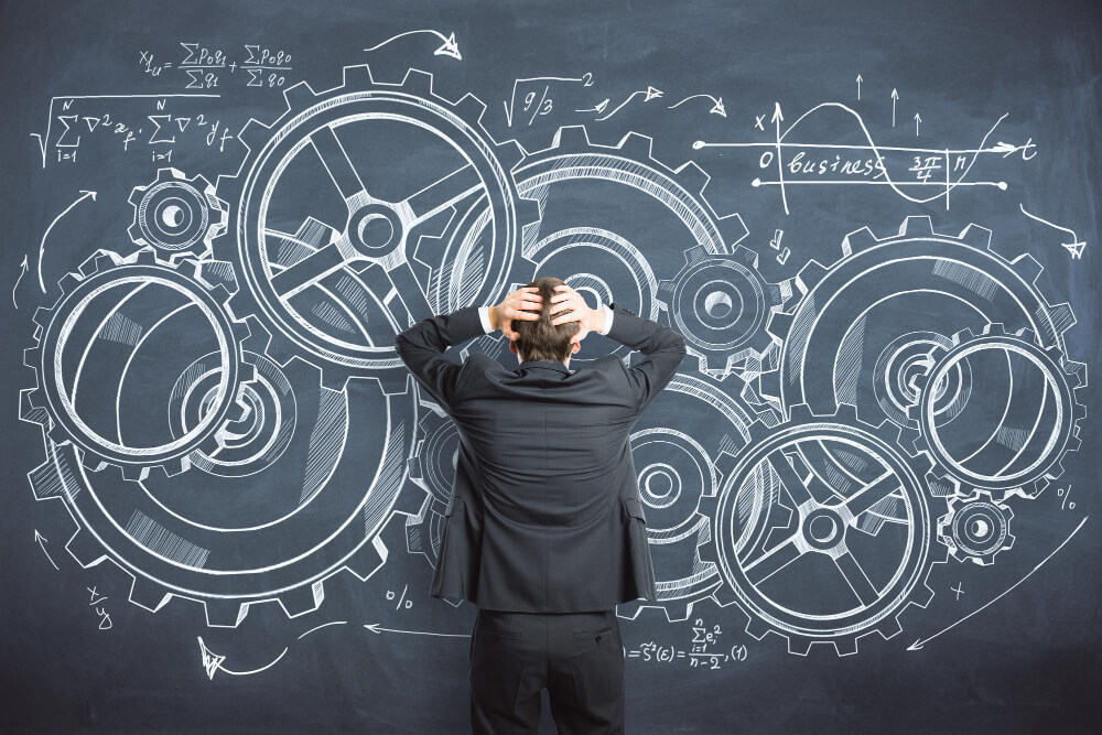 Person steht vor einer Tafel mit komplexen Zahnrädern und Formeln – Symbol für die Herausforderungen im Risikomanagement Medizinprodukten.